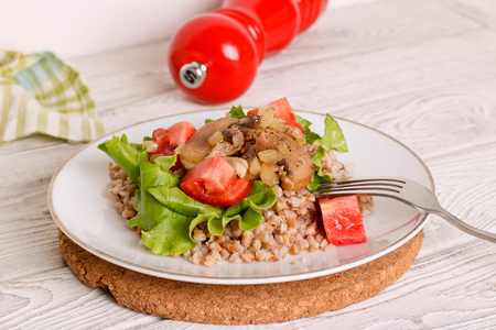 Buckwheat porridge with mushrooms and onions on a white plateの写真素材