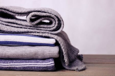 A stack of sweatshirts and a scarf on a neutral background.の写真素材