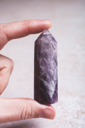 Amethyst mineral stone in a female hand on a white background. Occultism concept.