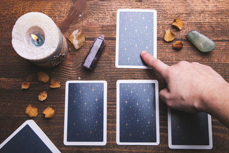 Fortune-telling tarot cards and mineral stones on a brown wooden background. Occultism concept.