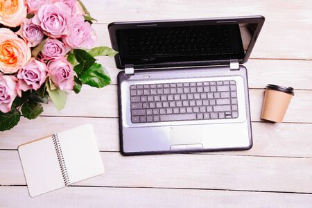 Laptop and bouquet of hybrid tea roses on a white background. Concept love online.の写真素材