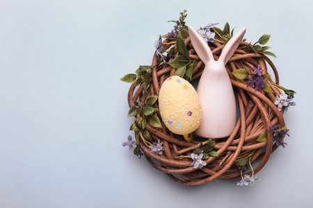 Ceramic Easter bunny and decorative colored egg in a wreath on a blue background.
