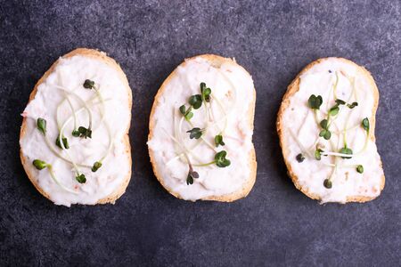Toasts with cream and radish microgreen on a black background.の写真素材