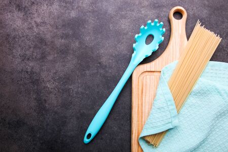 Spaghetti and spoon for spaghetti on a cutting board on a black background.の写真素材