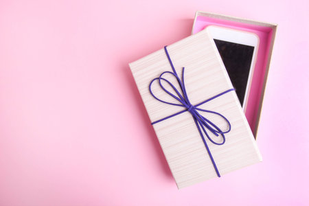 Smartphone in a gift box on a pink background.