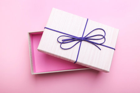 Open beige gift box on a pink background.