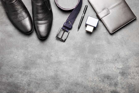 Classic black leather shoes with a belt and other accessories on a black background. Men's clothing.の写真素材