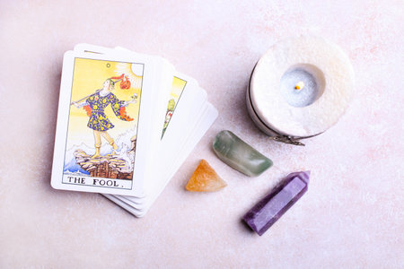 A deck of tarot cards and mineral stones on white background.