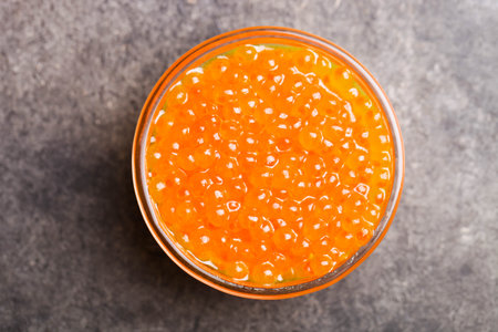 Red chum salmon caviar in glass bowl on black background.の写真素材