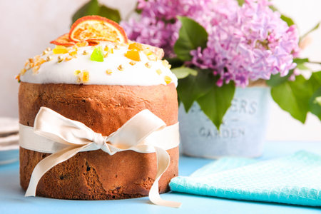 Easter cake with candied fruits and a branch of lilac on a blue wooden background.
