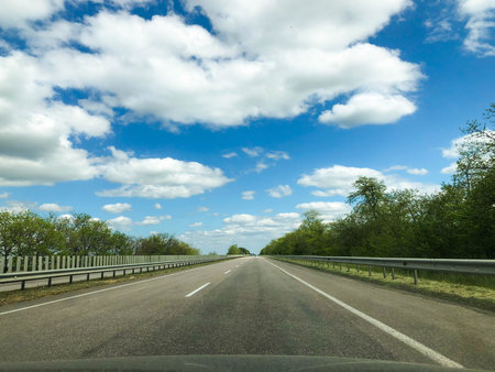 Asphalt straight road and blue sky with clouds on a summer day. Travel.