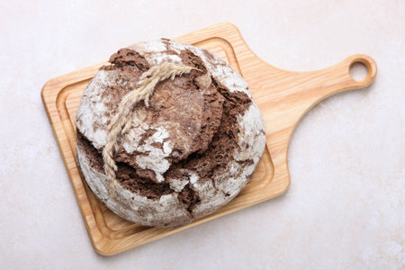 Homemade rye bread on a cutting board on white background.