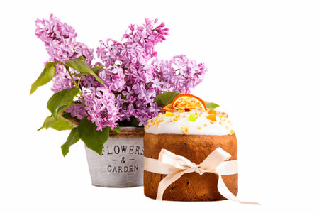 Easter cake with candied fruits and a bouquet of lilacs isolated on white background.