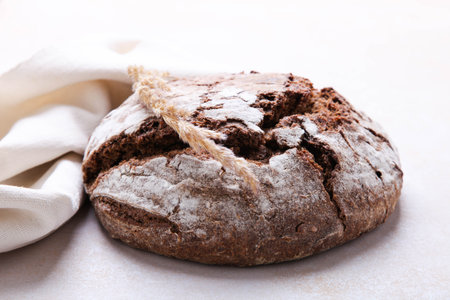 Homemade rye bread, sprinkled with flour, on white background.