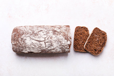 loaf of rye bread, cut into slices on white background.