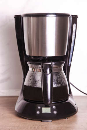 Drip coffee maker with hot coffee on the table.の写真素材