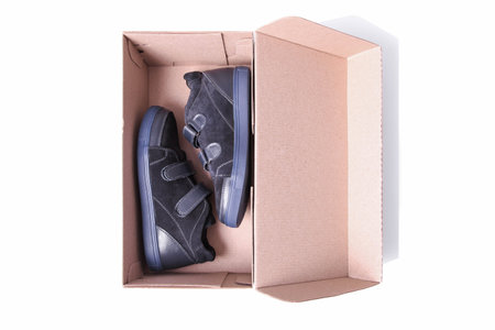 Pair of childrens suede demi-season boots in cardboard box isolated on white background.