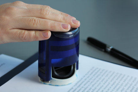 woman's hand puts a stamp on the documents. contact signing.