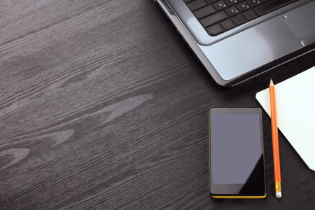 Gadgets and notepad on a black wooden background. workplace.