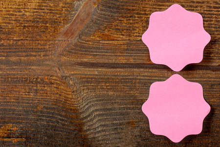 pink paper stickers glued on wooden Board with place for textの写真素材