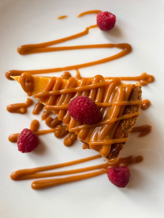 Caramel cheesecake with raspberries on plate in cafe, top view.の写真素材