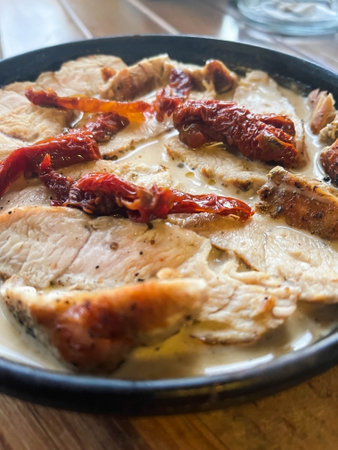 Turkey fillet with sun-dried tomatoes in creamy sauce in frying pan.の写真素材
