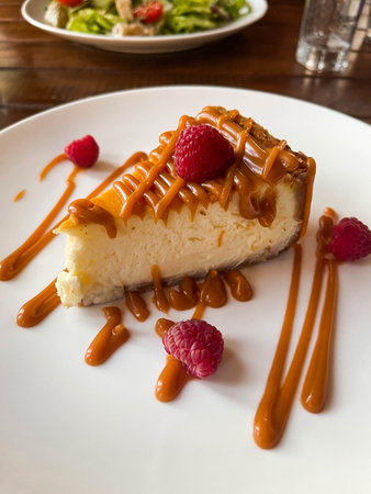 Caramel cheesecake with raspberries on plate in cafe.