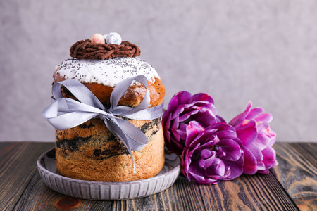 Easter cake tied with ribbon and flowers on brown wooden background.の写真素材