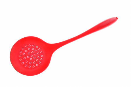 Red colander with plastic handle isolated on white background.の写真素材