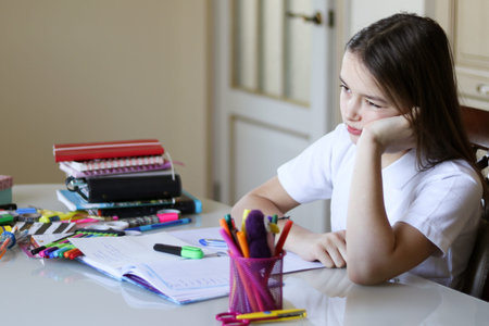 Young schoolgirl is upset and tired of doing school homework at home