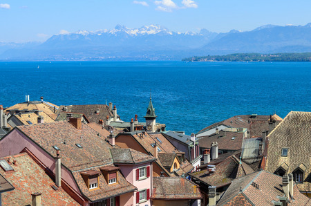 Beautiful view at Geneva lake and french Alps mountains with snow tops through roofs of old town of Nyon, Switzerlandの写真素材