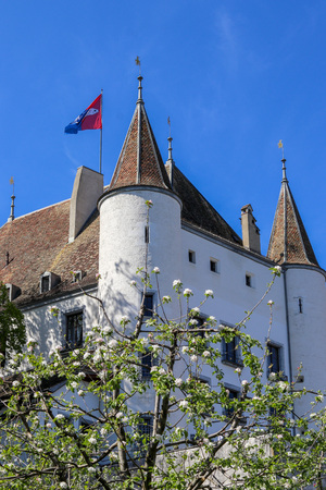 View at Nyon castle with flag waving on the roof through blooming tree, Switzerlandのeditorial素材