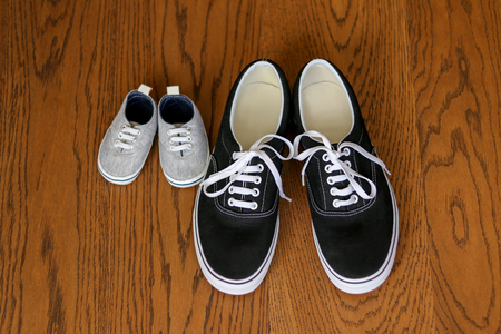 Father and son sneakers staying next on the wooden floor, top view. Fathers dayの写真素材