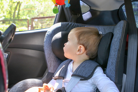 Cute little baby boy in car safety seat looking at the window. Traveliing with child and baby transportation safety conceptの写真素材