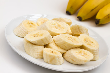 close up of sliced banana on a plate with unpeeled bananas in the backgroundの写真素材
