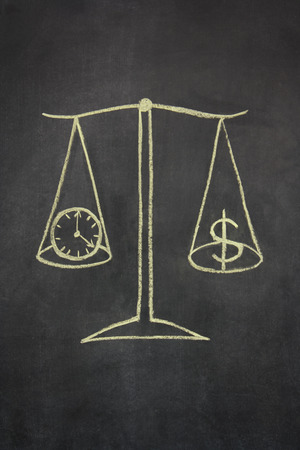 drawing on a chalkboard of a set of scales, with money symbol on one side and a clock on the otherの写真素材