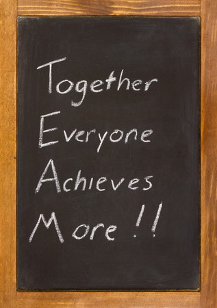 Small chalkboard with a wooden frame with together everyone achieves more written on it in white chalk.の写真素材