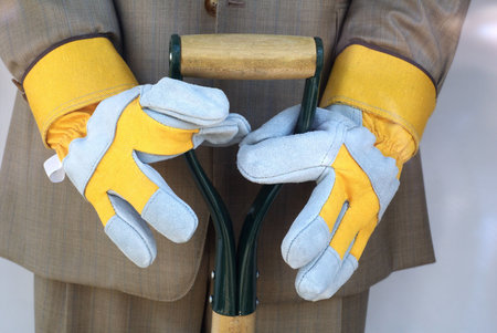 male mannequin holding shovel in business suit with garden gloves - busy life metaphor