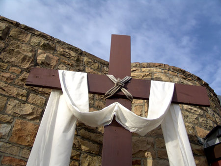 cross with cloth in front of stone wall