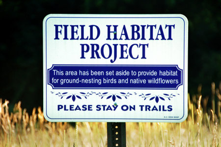 a field habitat project sign to protect ground-nesting birds and native wildflowersの写真素材