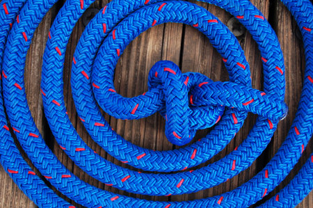 blue and red speckled nautical rope coiled and knotted securing boat to dockの写真素材