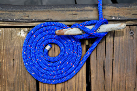 coiled blue rope securing boat to wooden dockの写真素材