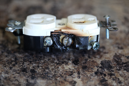 Burned electrical wall outlet with melted plasticの写真素材