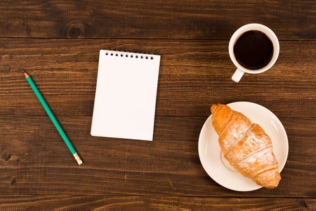 breakfast with cup of black coffee, croissants, notebook with a penの写真素材