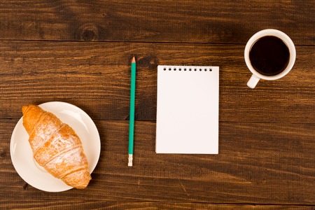 breakfast with cup of black coffee, croissants, notebook with a penの写真素材