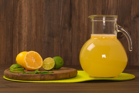 Lemonade with fresh lemon and mint in glass jug on wooden backgroundの写真素材