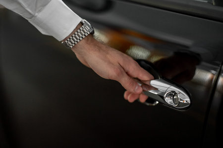 male hand holds a black car door handle