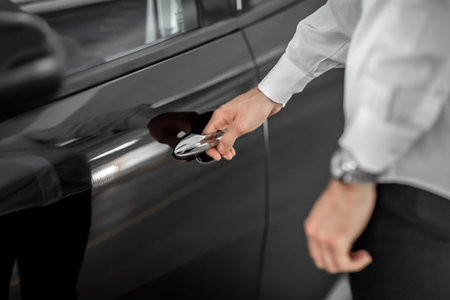 male hand holds a black car door handle