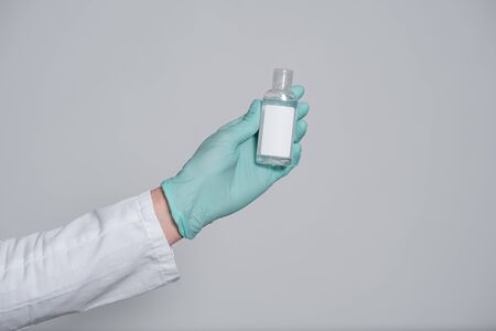 antiseptic gel for protection against infectious viruses in the hand in a  blue medical glove, bacteria and germs on a gray backgroundの写真素材