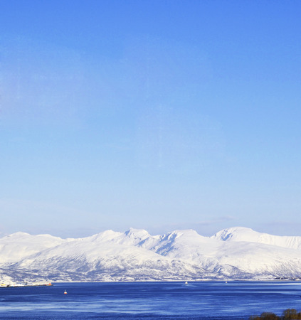 Blue clear sky, snowy mountains and blue seaの写真素材